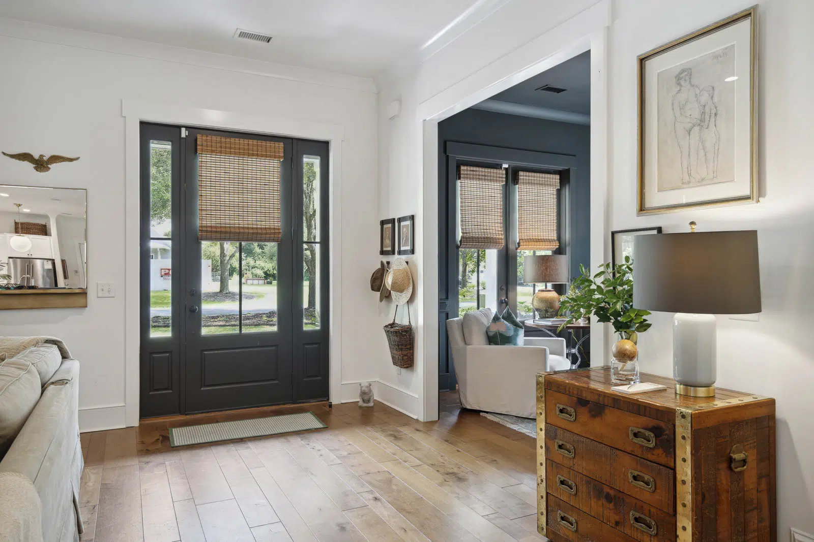Entryway with home decor including framed drawing, hats hanging from hook, and wood chest.