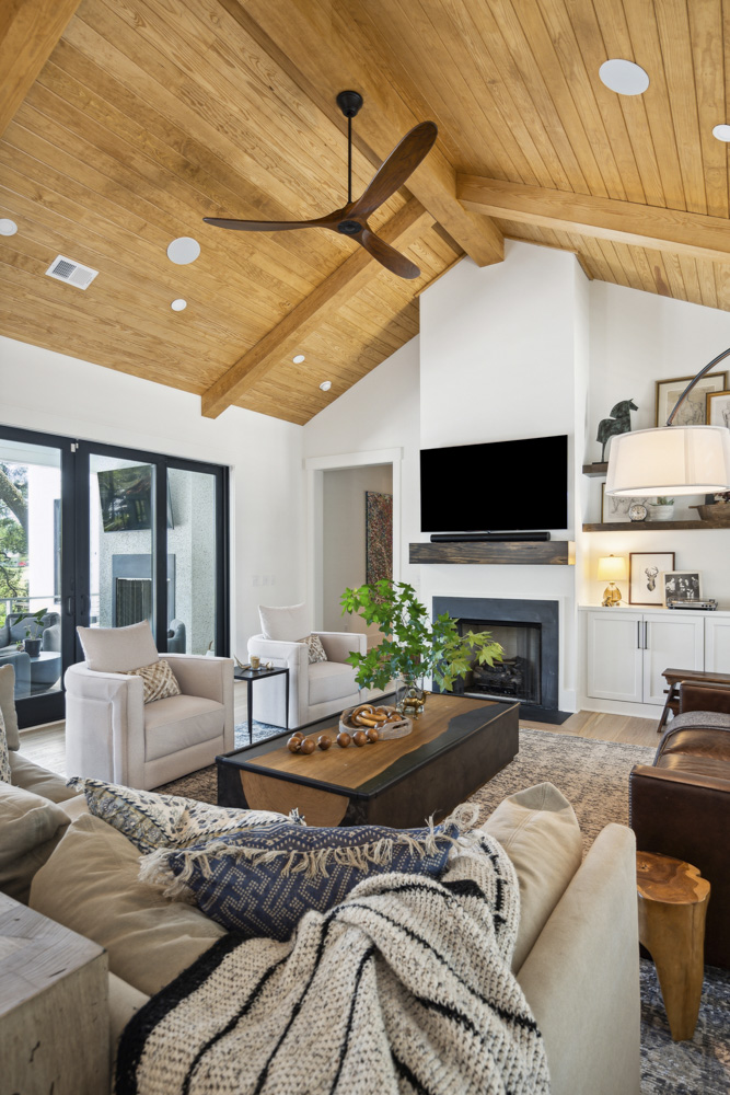 Armchairs and coffee table with home decor. Wooden vaulted ceiling with fan.