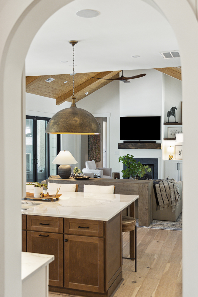 Kitchen and living room furnishings and home decor as seen through arched entryway