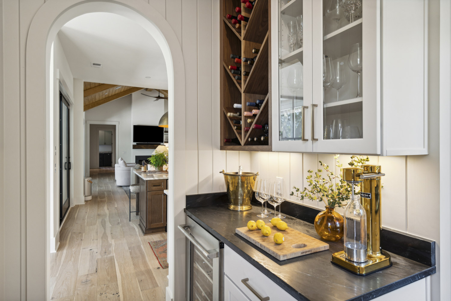Cocktail bar with lemons on cutting board, wine glasses and arched doorway to the kitchen