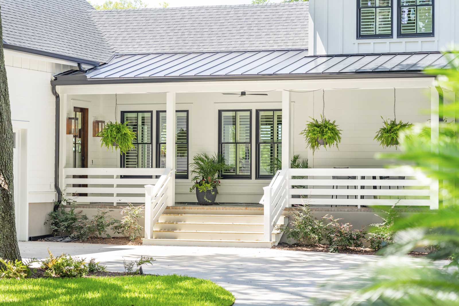 Front porch decor including potted plants and hanging fern baskets