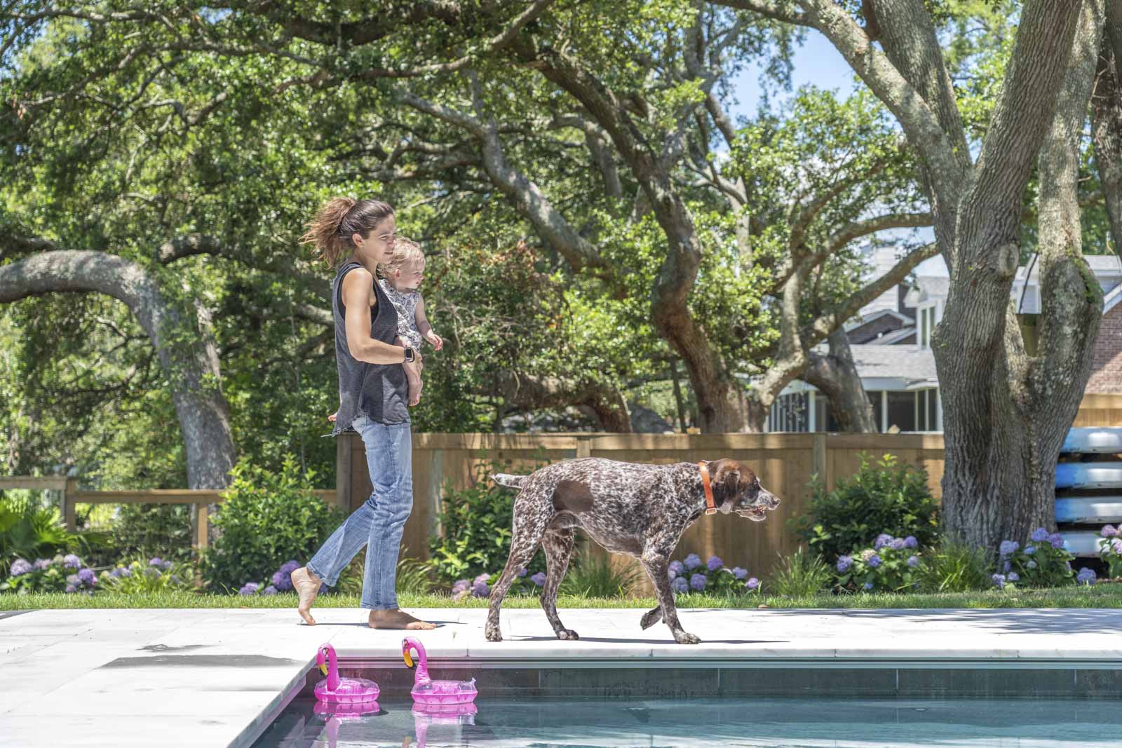 Mother, daughter, and dog in backyard with swimming pool