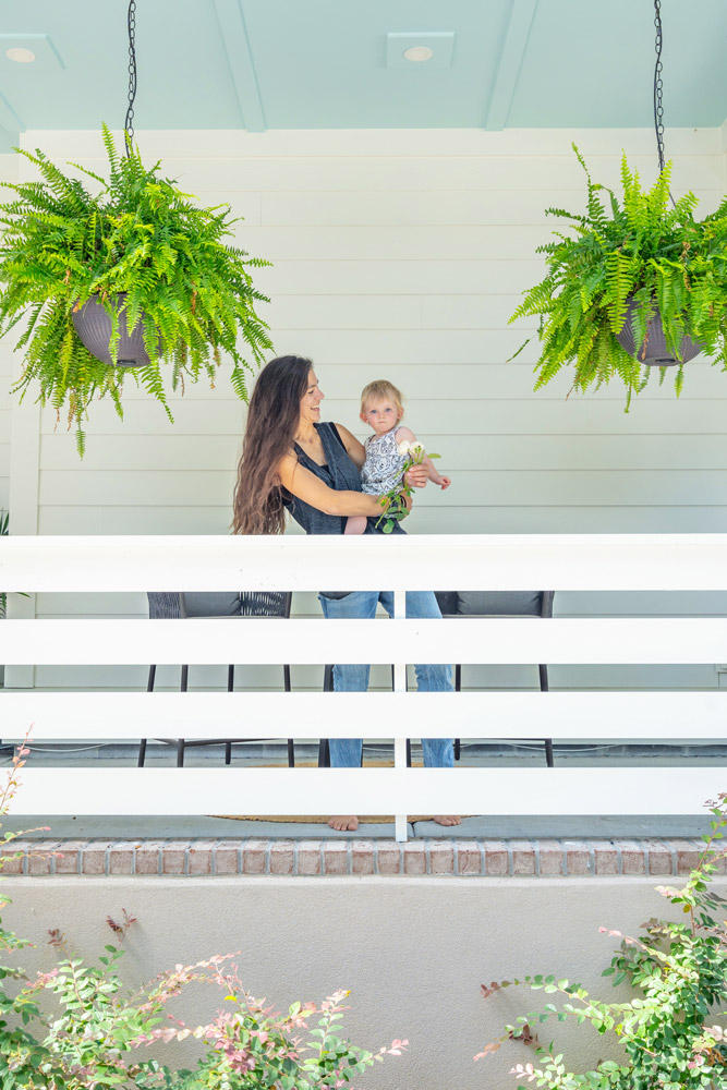 Mother and daughter at front porch with hanging ferns